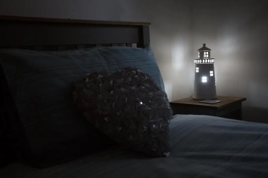 a dark room with a bed and a lighted lighthouse at Seaesta Apartments in Macduff