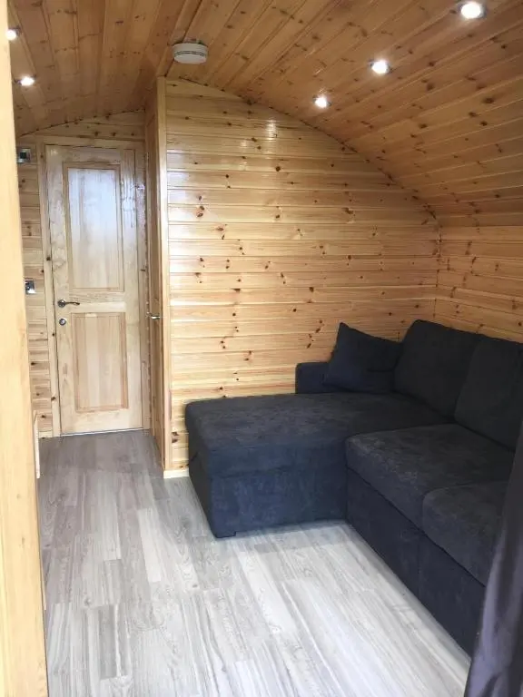 a couch in a room with a wooden wall at Greencraig Pods in Buckie