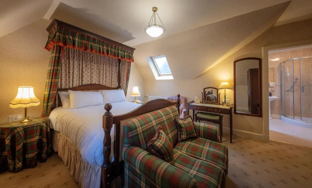 a bedroom with a bed and a couch and a tub at Glengarry Castle Hotel in Invergarry