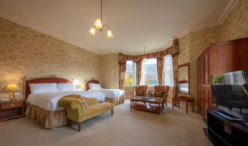 a bedroom with a large bed and a television at Glengarry Castle Hotel in Invergarry