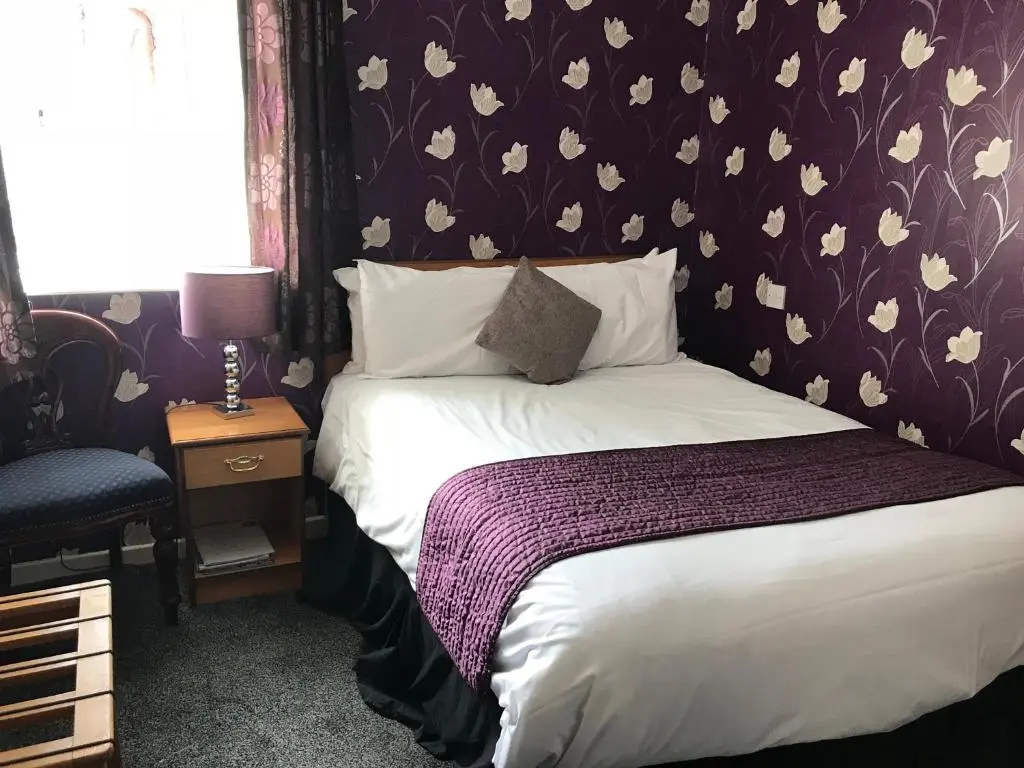 a bedroom with a bed with a flower patterned wall at The Old Coach House in Buckie