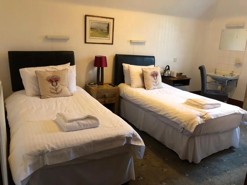 a bedroom with two beds with white sheets at Westerlea Hotel Nairn in Nairn