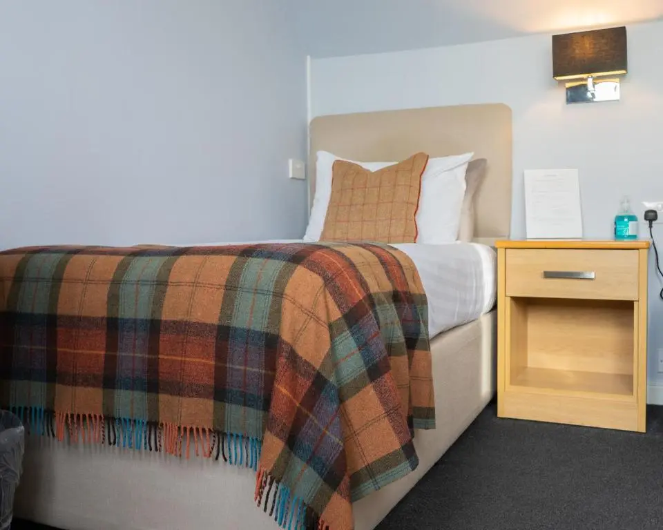 a bedroom with a bed with a blanket and a night stand at Firth Hotel & Restaurant in Lossiemouth