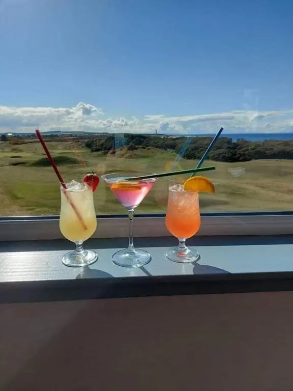 three cocktails sitting on a ledge in front of a window at GOLF View Hotel & Macintosh Restaurant in Lossiemouth