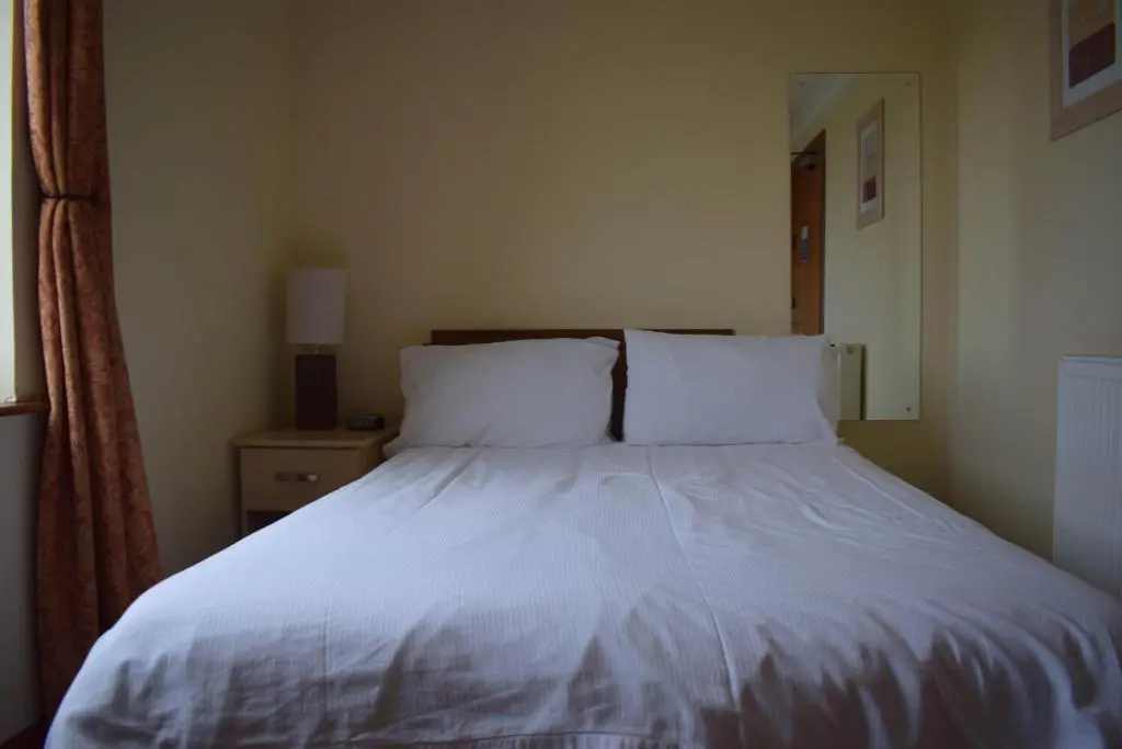 a bed with white sheets and pillows in a bedroom at GOLF View Hotel & Macintosh Restaurant in Lossiemouth