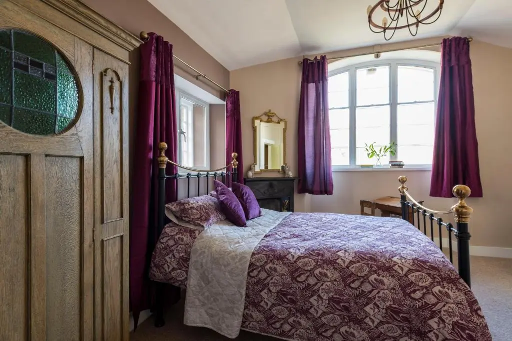 a bedroom with a bed with purple curtains at Evelix, The Old School House in Muir of Ord