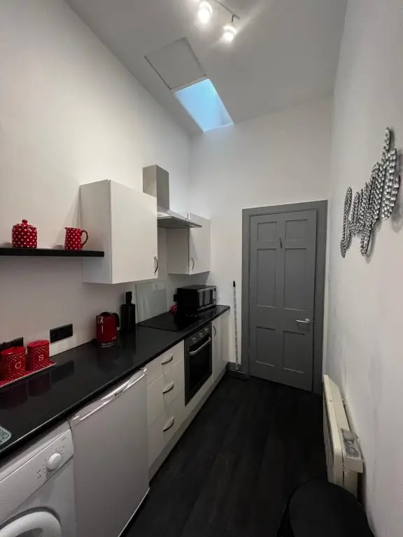 a kitchen with white cabinets and a black counter top at The Sheriffs Lodge in Dingwall
