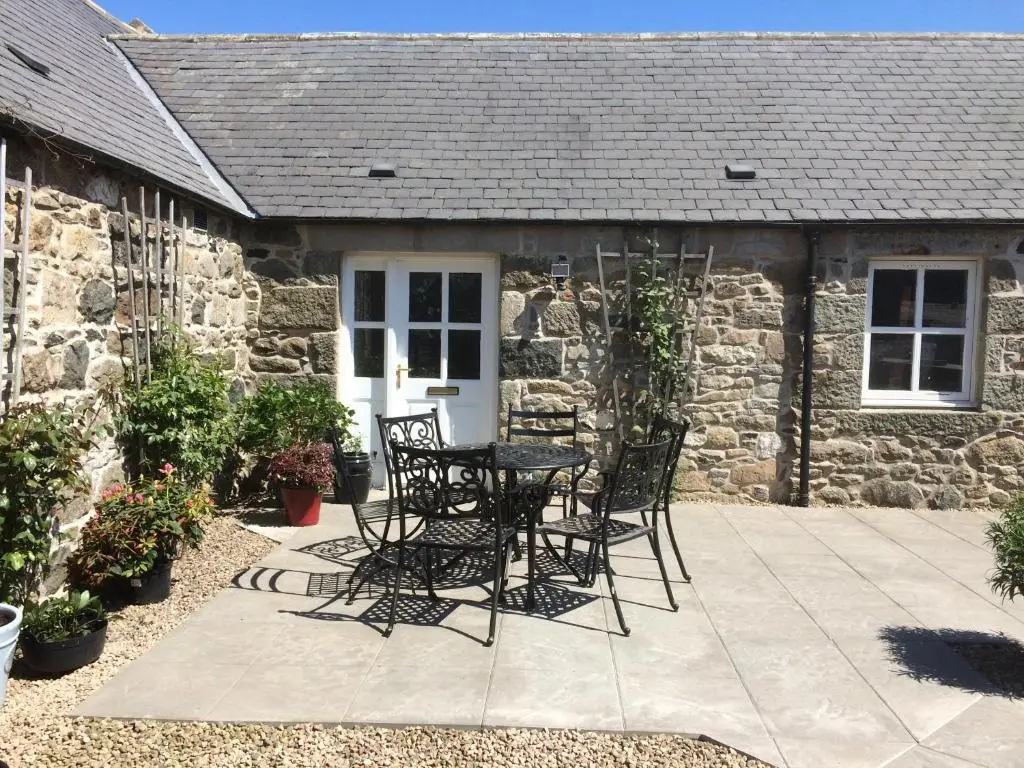 a table and chairs in front of a stone cottage at LAIRDS COTTAGE in Stuartfield