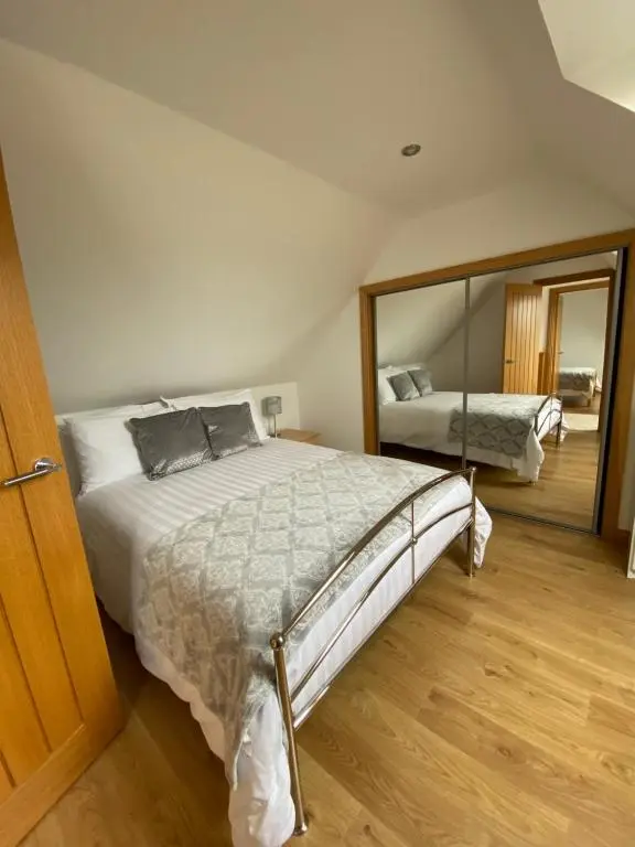 a bedroom with a large bed and a mirror at LAIRDS COTTAGE in Stuartfield