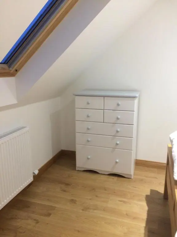 a bedroom with a dresser in a attic at LAIRDS COTTAGE in Stuartfield