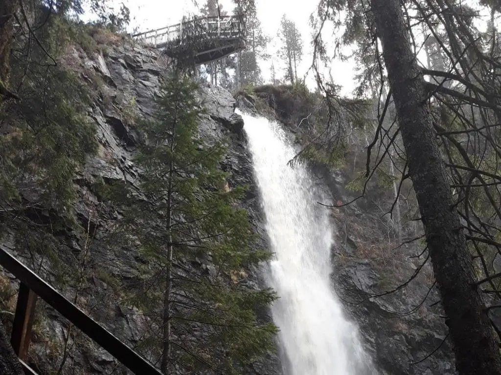 a waterfall on the side of a mountain with a bridge at Loch Ness Studio Blairbeg in Drumnadrochit