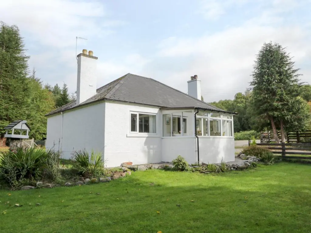 a small white house with a grass yard at St Aethans in Inveran