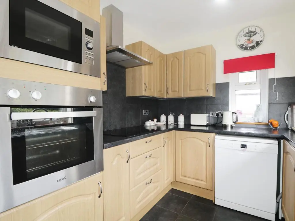 a kitchen with wooden cabinets and stainless steel appliances at St Aethans in Inveran