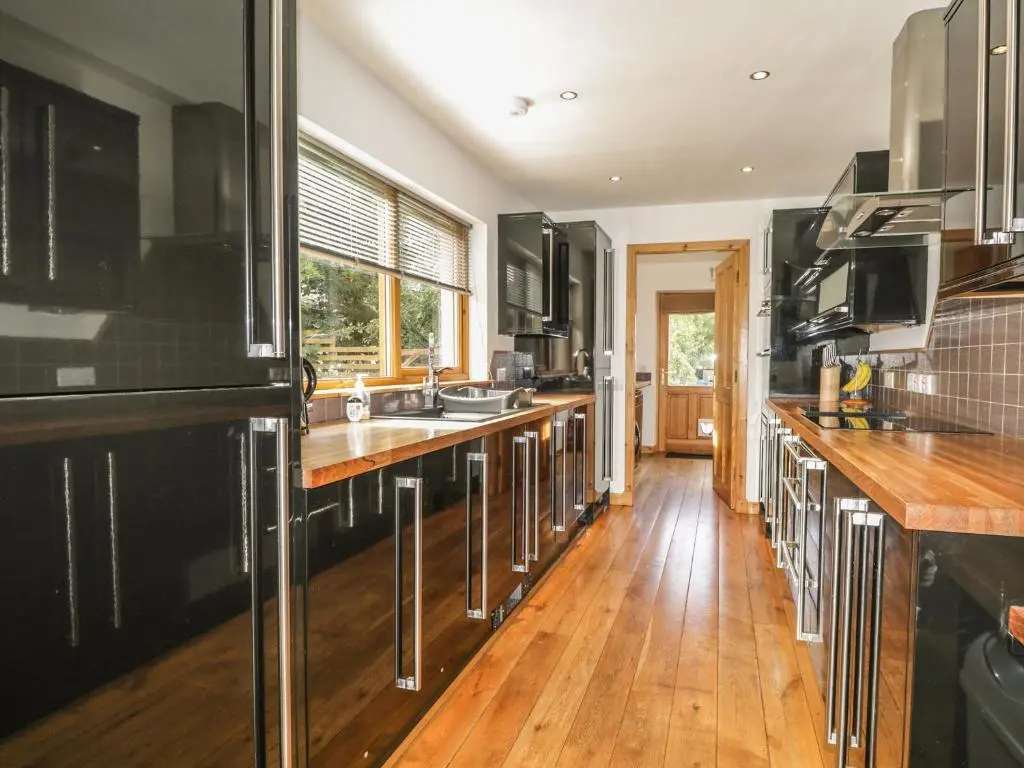 a kitchen with black cabinets and wooden floors at Dolce Casa in Grantown on Spey