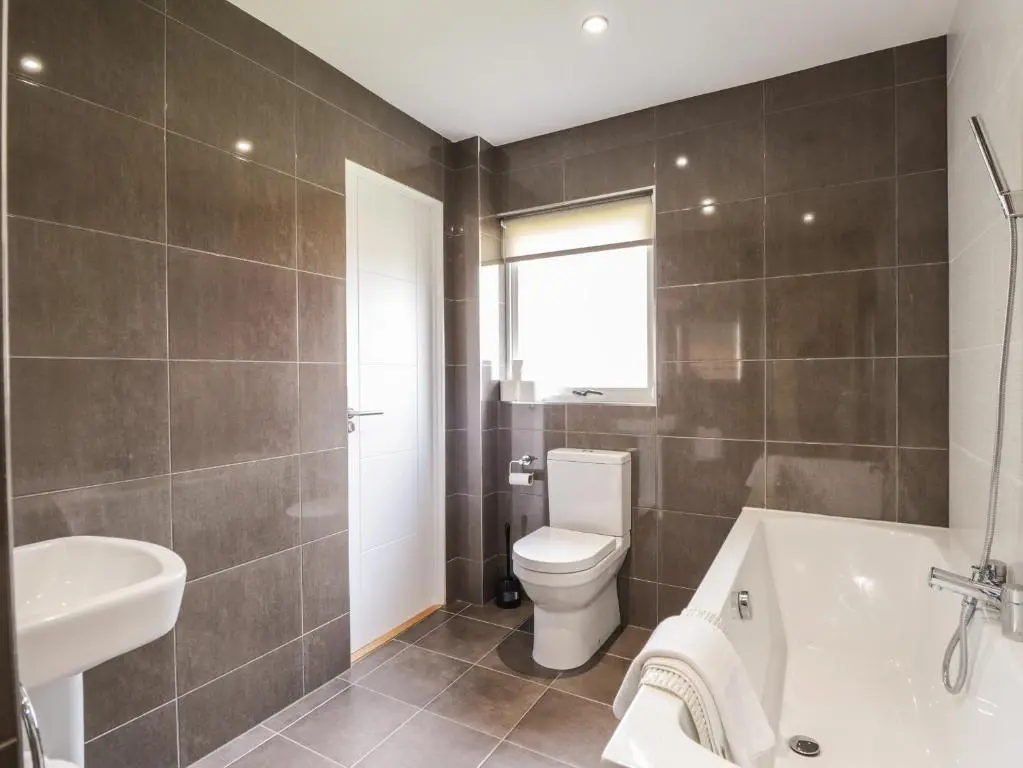 a bathroom with a toilet and a tub and a sink at Millview in Boat of Garten