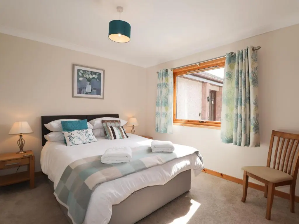 a bedroom with a bed and a window and a chair at Millview in Boat of Garten