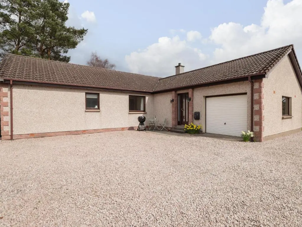 a house with a garage and a gravel driveway at Millview in Boat of Garten