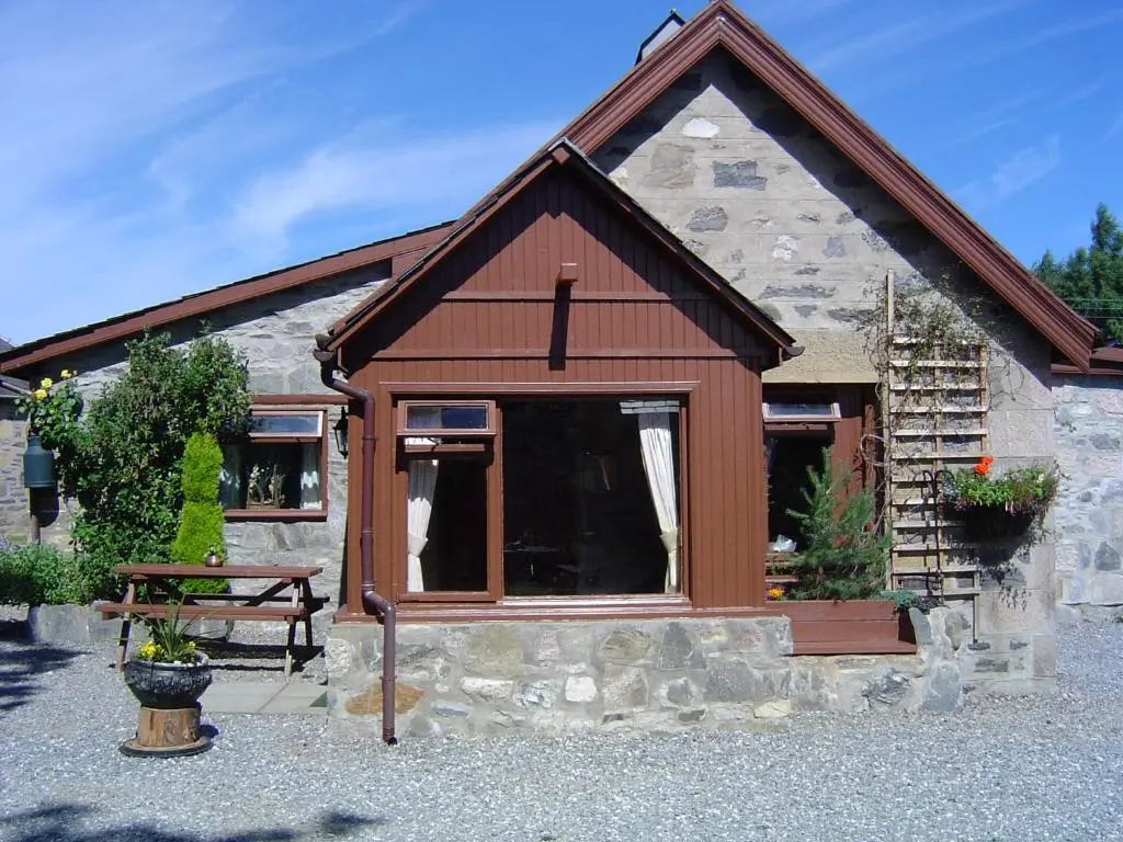 a building with a window and a bench in front of it at Islay Cottage, Meadowside, Kincraig, near Kingussie in Kincraig