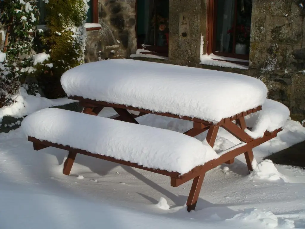 two benches covered in snow in front of a house at Islay Cottage, Meadowside, Kincraig, near Kingussie in Kincraig