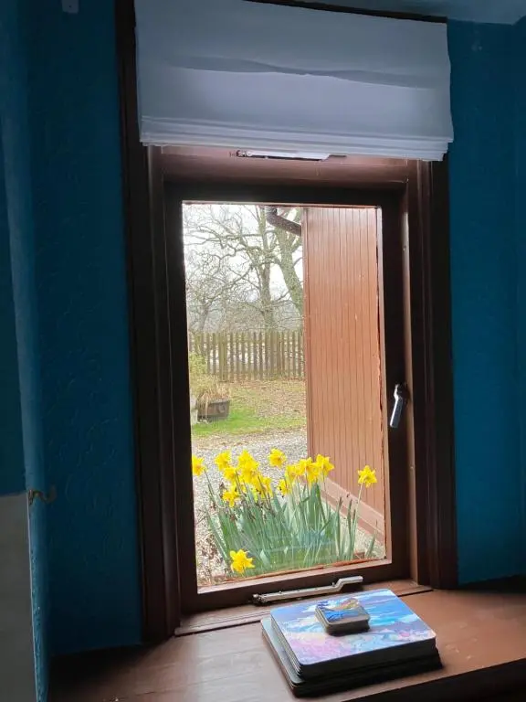 a window with a view of a field of flowers at Islay Cottage, Meadowside, Kincraig, near Kingussie in Kincraig