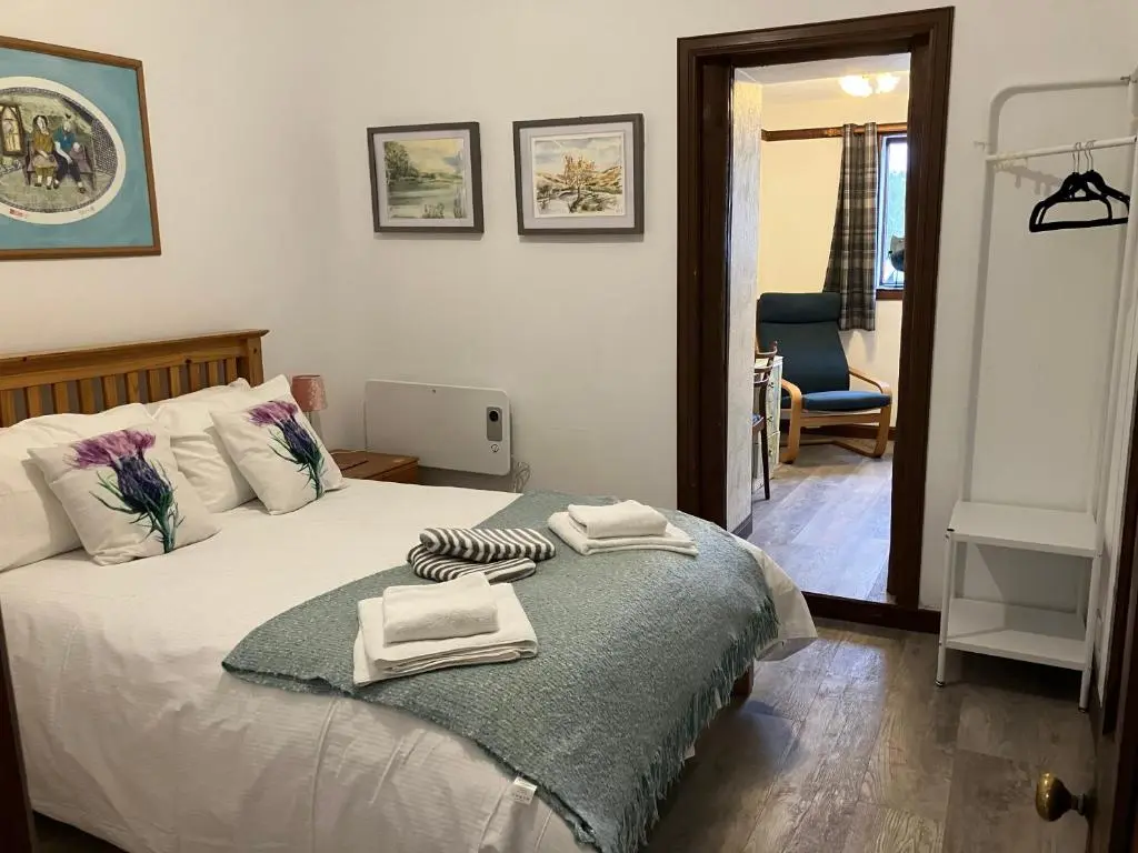 a bedroom with a bed with towels on it at Islay Cottage, Meadowside, Kincraig, near Kingussie in Kincraig