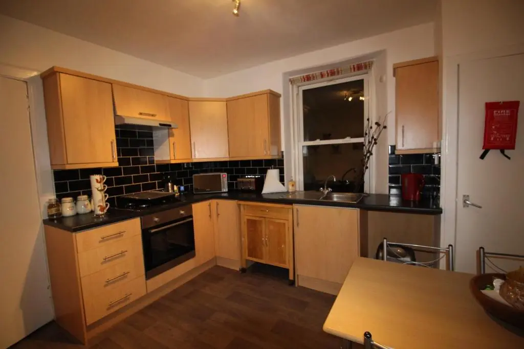 a small kitchen with wooden cabinets and a table at 63 Argyle Street in Inverness