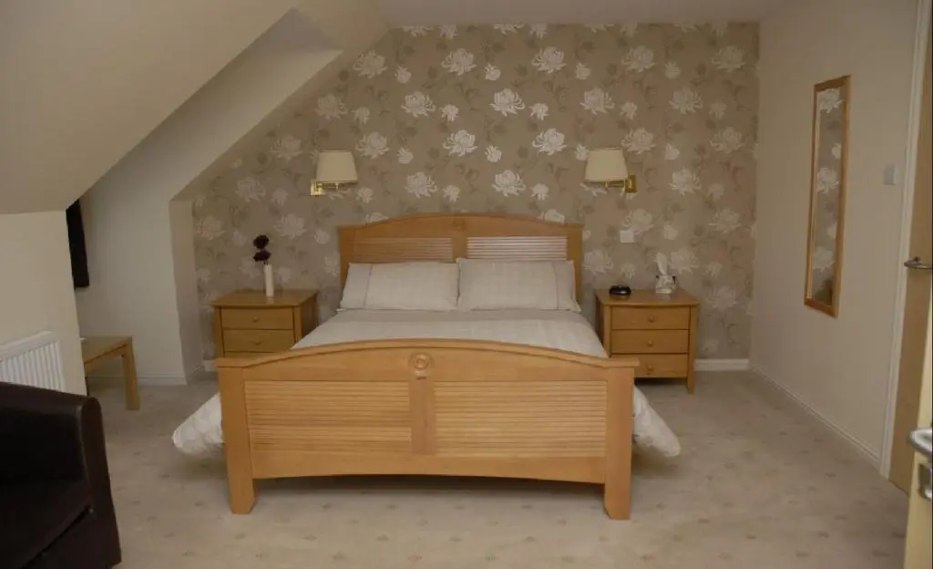 a bedroom with a wooden bed and two night stands at Ban Car Hotel in Cairness