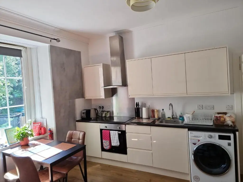 a kitchen with white cabinets and a table and a sink at CHARMING VICTORIAN APARTMENT, close to centre in Inverness
