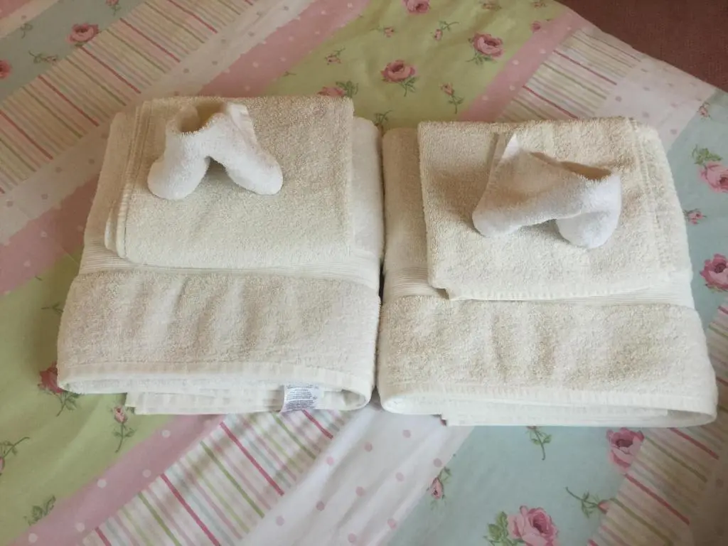 two towels sitting on top of a bed at New Cottage 3 Bedroom Free Parking in Inverness
