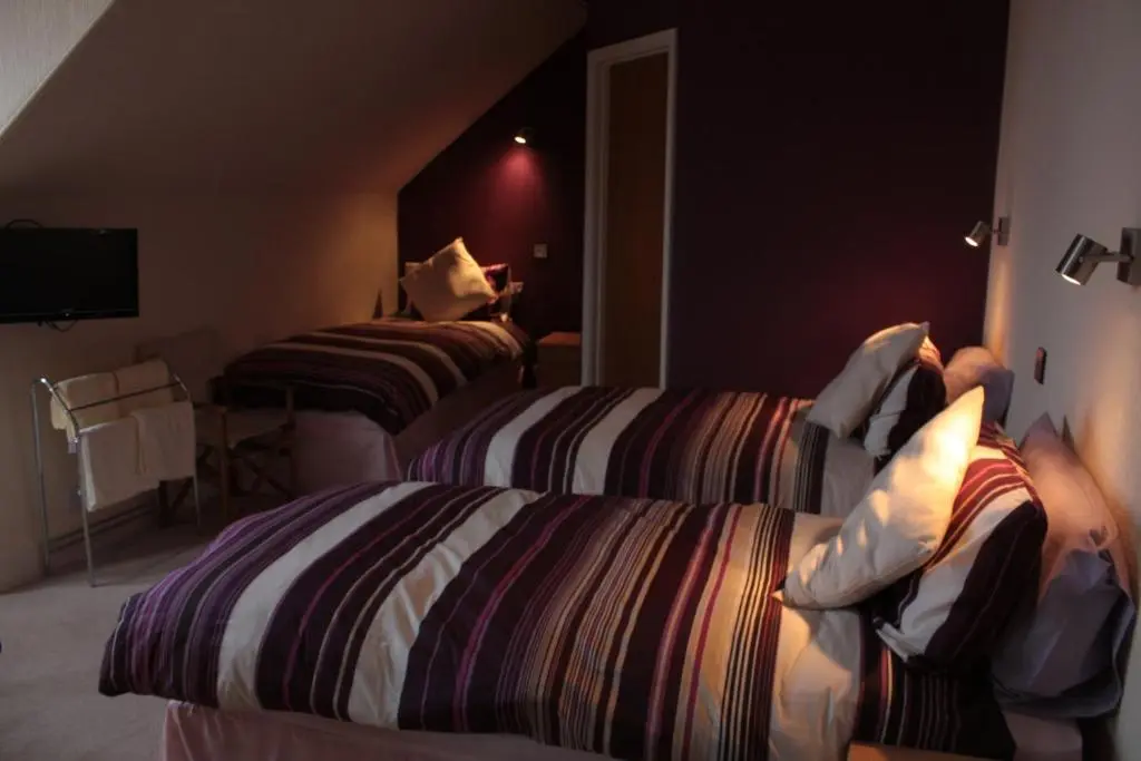 a hotel room with two beds and a tv at Harbour House Bed & Breakfast - Wick in Wick