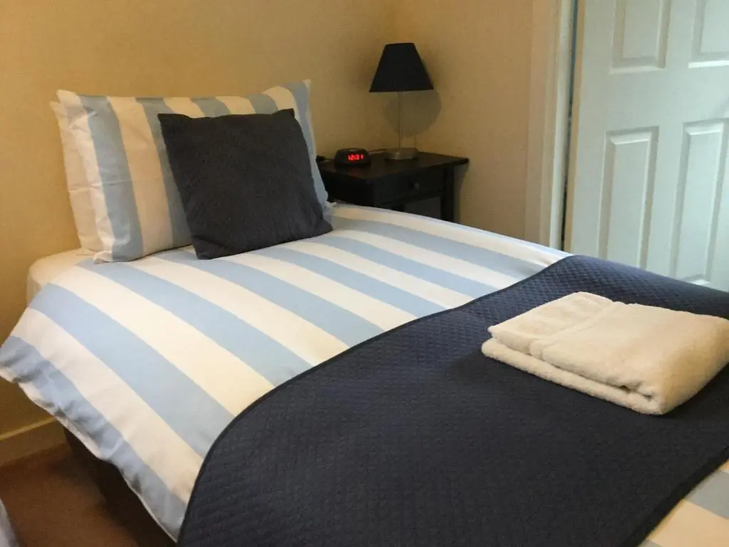 a blue and white bed with a towel on it at Darroch View B&B in Invermoriston