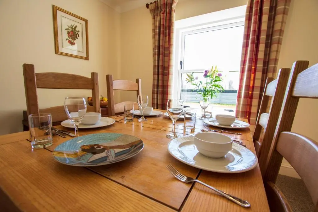 a dining room table with plates and glasses on it at Balnagown Estates in Kildary