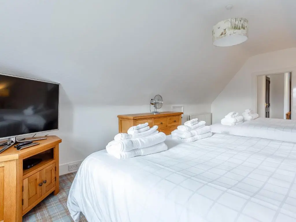 a bedroom with two beds and a flat screen tv at Craigendarroch House in Ballater