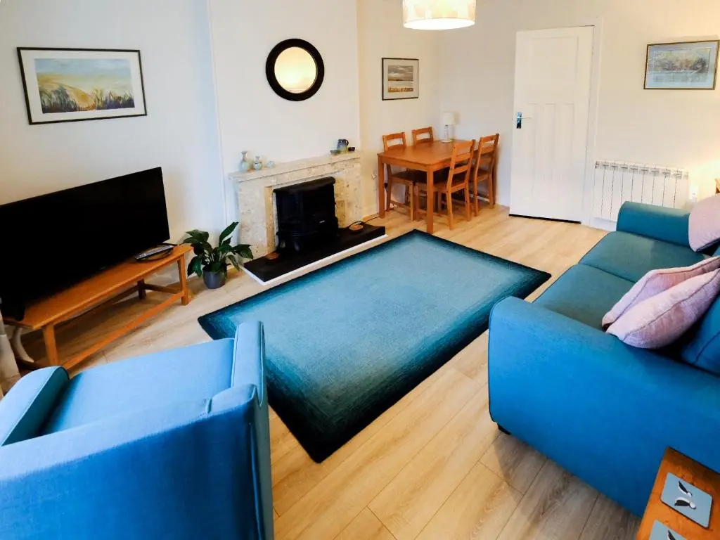 a living room with a blue couch and a fireplace at Fisher's Cottage in Balintore