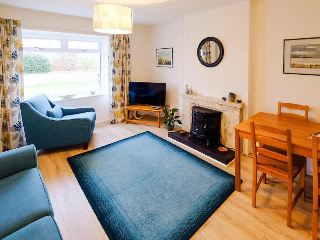 a living room with a table and a fireplace at Fisher's Cottage in Balintore