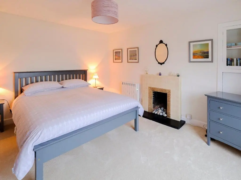 a bedroom with a bed and a fireplace at Fisher's Cottage in Balintore