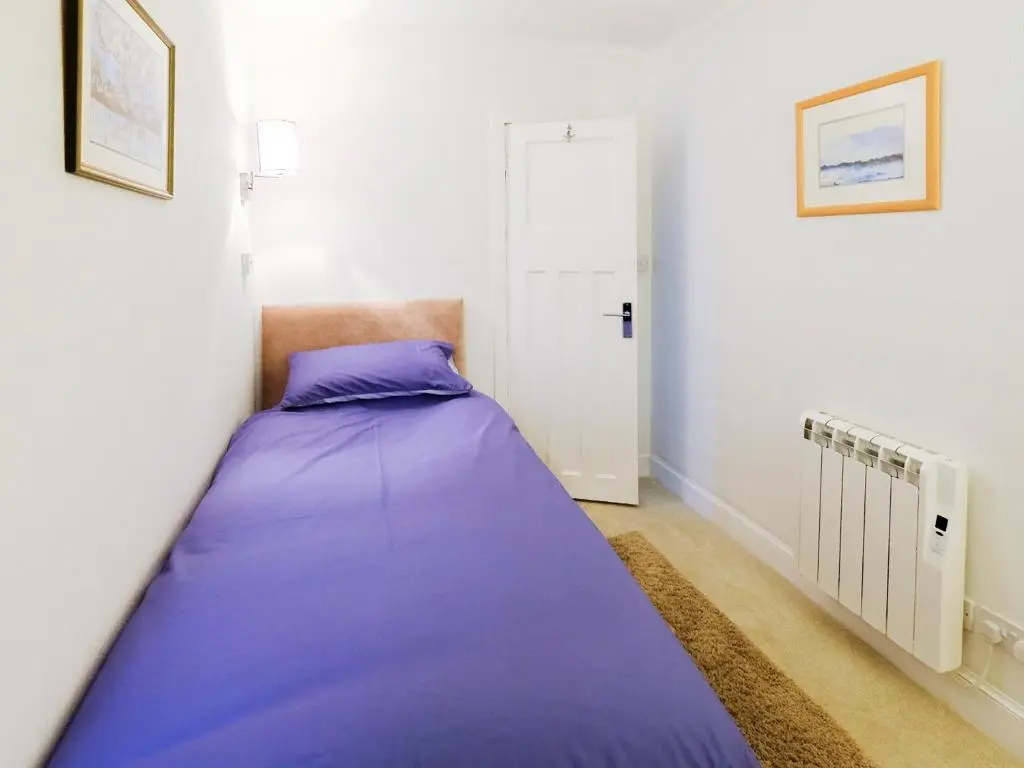 a small bedroom with a purple bed in it at Fisher's Cottage in Balintore