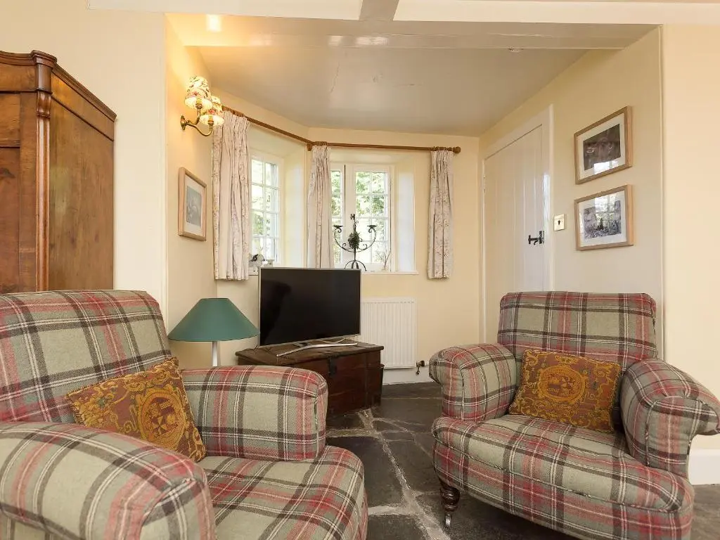 a living room with two chairs and a television at Big Barns Cottage in Backies
