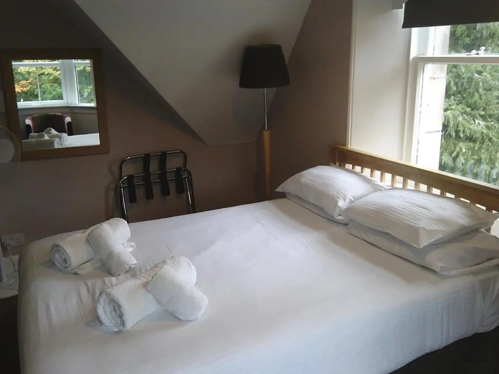 a bedroom with a large white bed with towels on it at The Speyside Hotel and Restaurant in Grantown on Spey