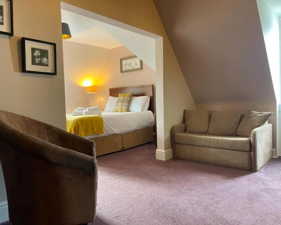 a bedroom with a bed and a couch and a chair at The Speyside Hotel and Restaurant in Grantown on Spey