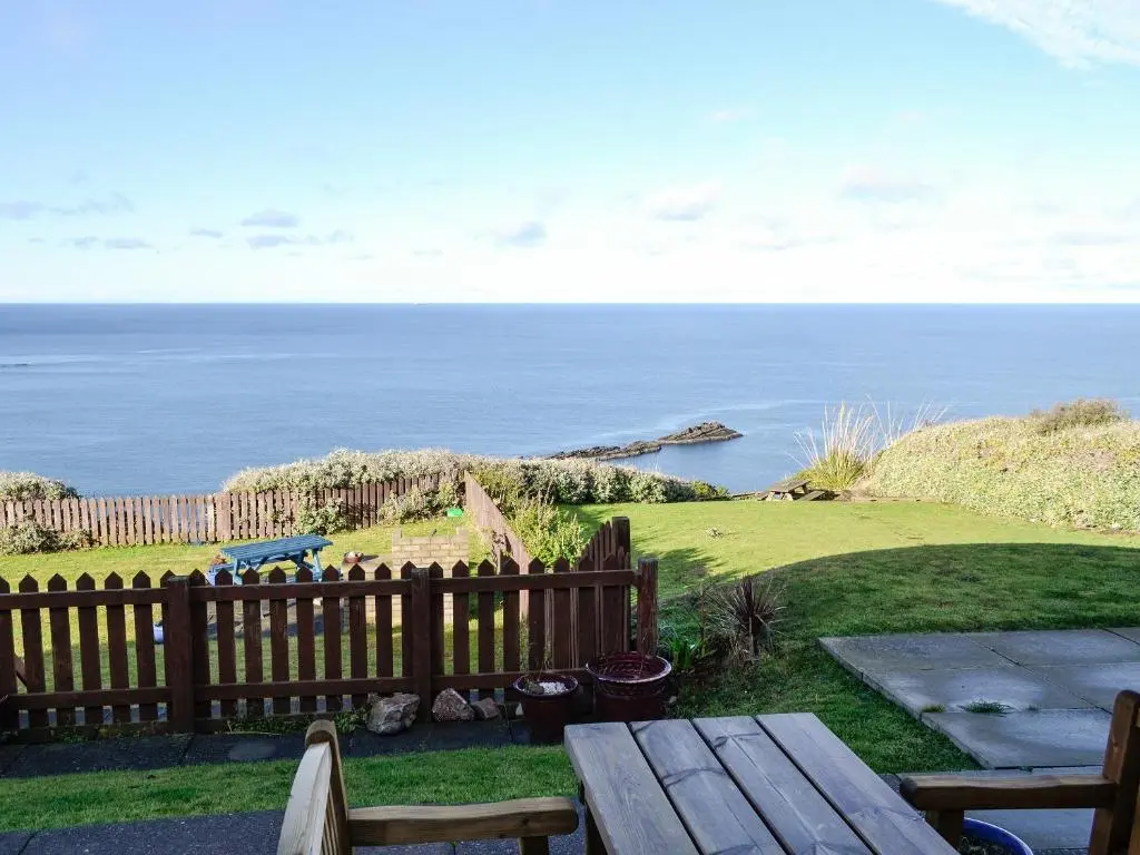 a wooden fence with a picnic table and the ocean at Ruach in Gardenstown