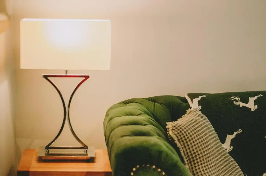 a lamp sitting on a table next to a green couch at The Black Isle Retreat in Inverness