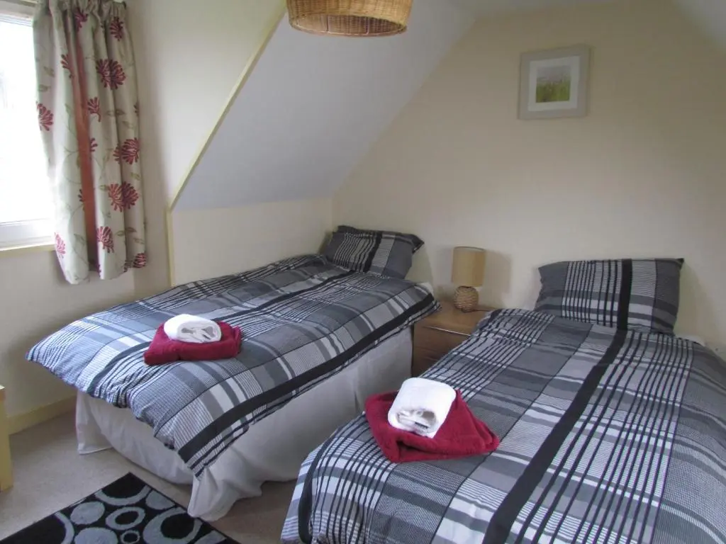 two beds in a bedroom with towels on them at Altnaharra Hotel in Lairg