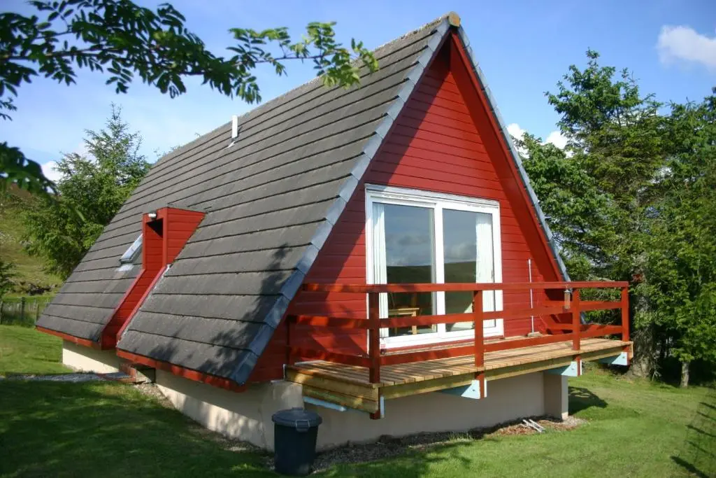 a red house with a window and a porch at Highland Glen Lodges in Rogart