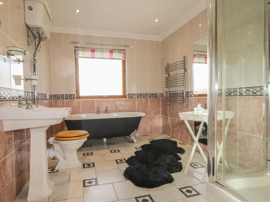 a bathroom with a tub and a toilet and a sink at The Glebe in Invergordon