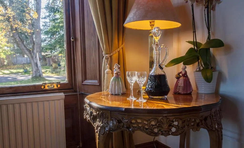a table with a lamp and wine glasses on it at Tigh na Sgiath Country House Hotel in Grantown on Spey
