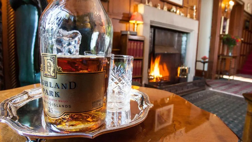 a bottle of whiskey sitting on a table with a glass at Tigh na Sgiath Country House Hotel in Grantown on Spey