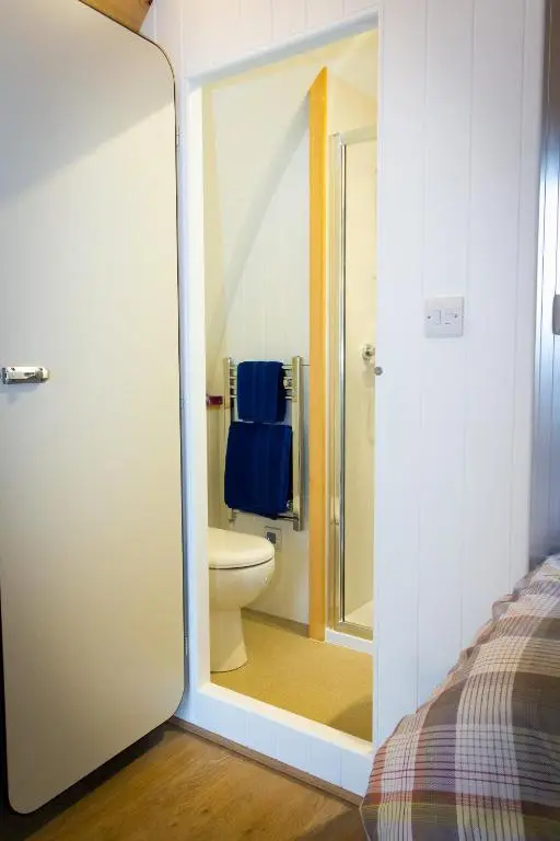 a bathroom with a toilet and a shower with a mirror at Evelix Pods Dornoch in Dornoch