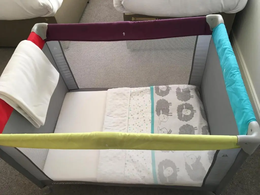 a crib with four different colored pillows at Riverbank Apartments in Nairn