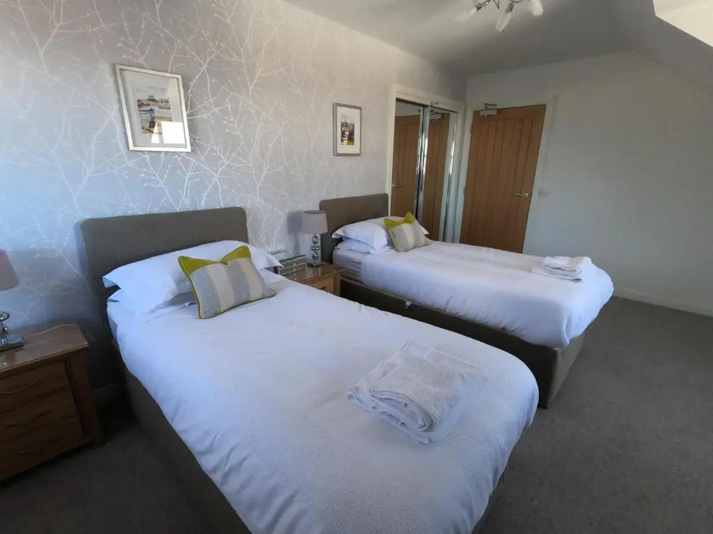 a hotel room with two beds with white sheets at Riverbank Apartments in Nairn